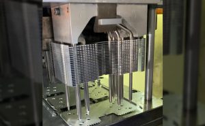 The stamping machine is running, and a cpu heat sink on the machine is assembling parts of its zippered fin