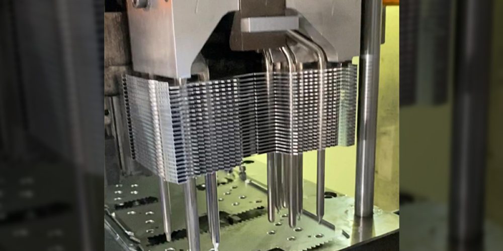 The stamping machine is running, and a cpu heat sink on the machine is assembling parts of its zippered fin